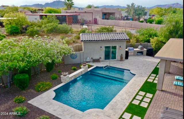 view of swimming pool featuring a patio, a mountain view, and an outdoor structure