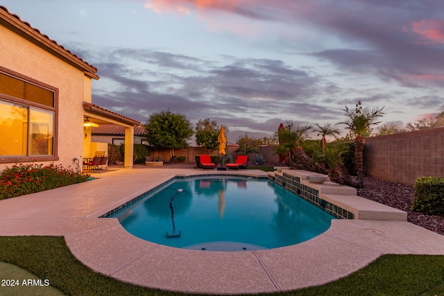 pool at dusk featuring a patio