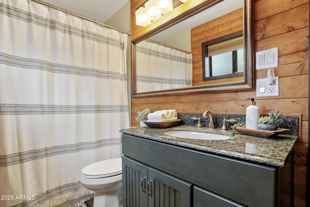 bathroom with vanity, toilet, and wood walls