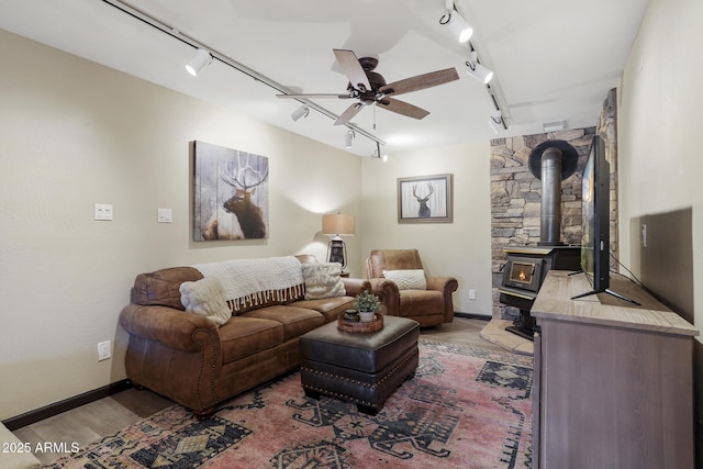 living room featuring hardwood / wood-style floors, rail lighting, ceiling fan, and a wood stove