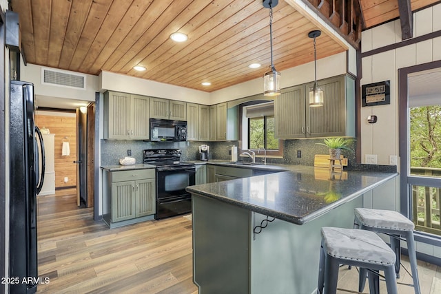 kitchen with sink, hanging light fixtures, a kitchen breakfast bar, kitchen peninsula, and black appliances