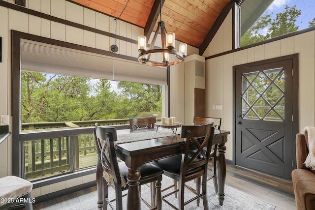 dining space with wooden walls, lofted ceiling, light hardwood / wood-style floors, wooden ceiling, and an inviting chandelier