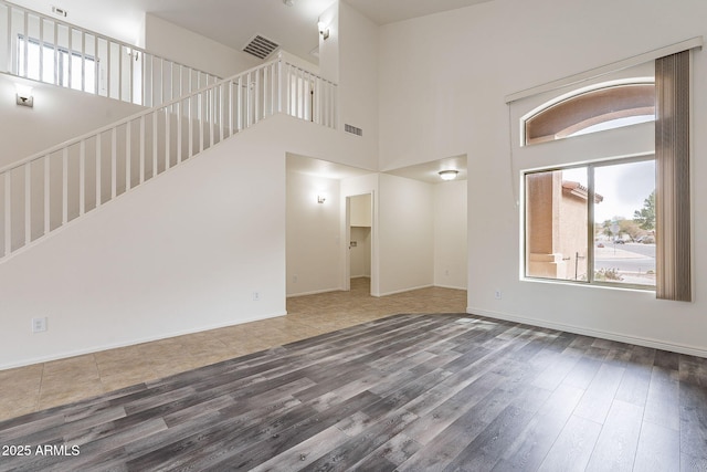 unfurnished living room featuring wood-type flooring and a high ceiling