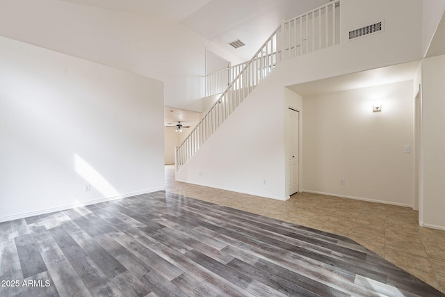 unfurnished living room with hardwood / wood-style flooring, ceiling fan, and a high ceiling