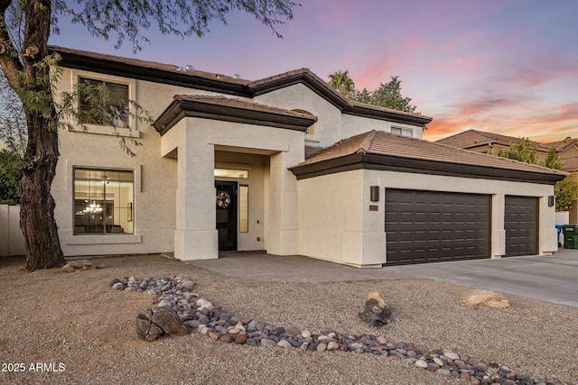 view of front facade featuring a tiled roof, an attached garage, and stucco siding