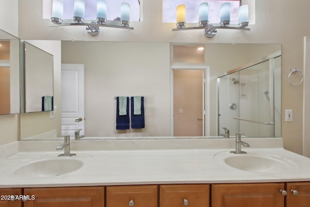 bathroom featuring a shower with door and vanity