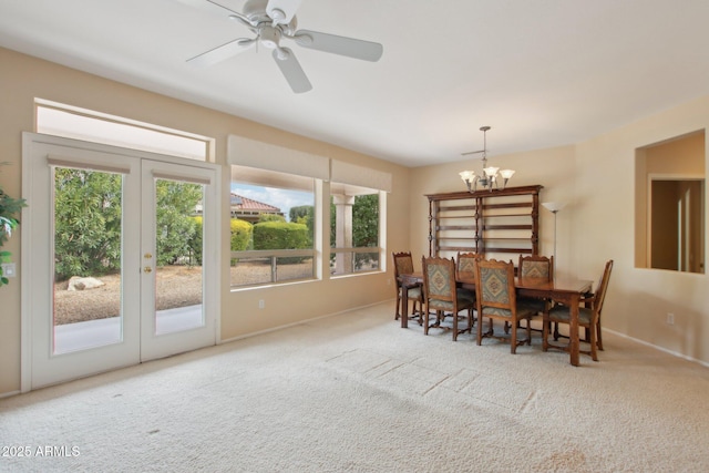 carpeted dining area with ceiling fan with notable chandelier and french doors