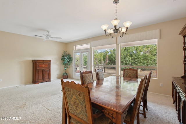 carpeted dining room featuring ceiling fan with notable chandelier and french doors