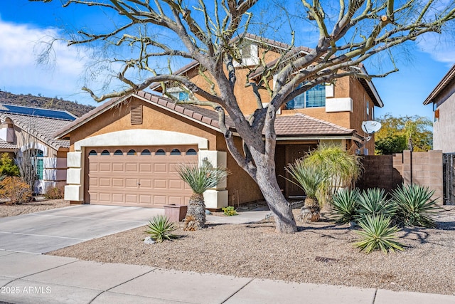 view of front of property featuring driveway, a tiled roof, an attached garage, fence, and stucco siding