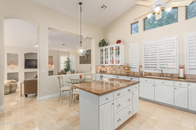 kitchen featuring pendant lighting, sink, dark stone countertops, a kitchen island, and white cabinetry