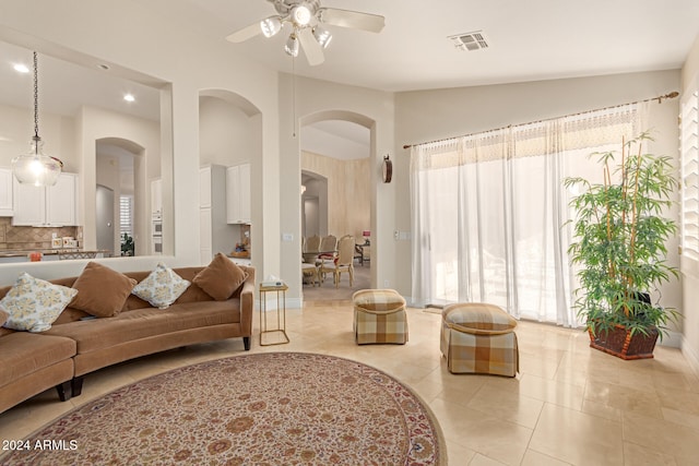 living room with ceiling fan, light tile patterned floors, and vaulted ceiling