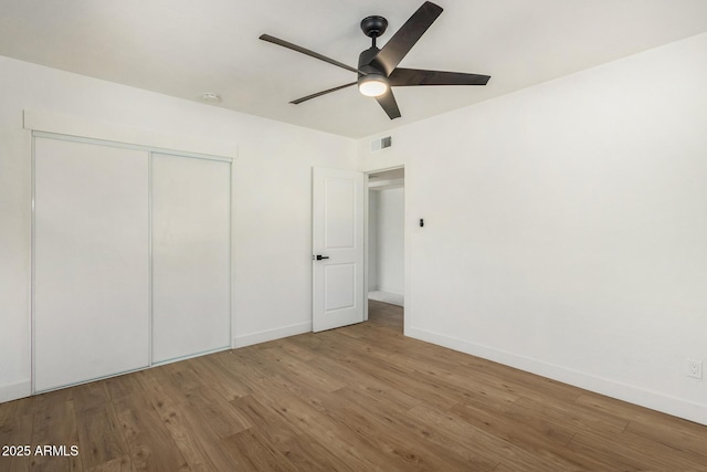 unfurnished bedroom featuring wood-type flooring, a closet, and ceiling fan