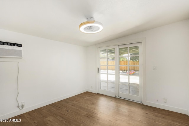 unfurnished room with vaulted ceiling, wood-type flooring, and a wall mounted air conditioner