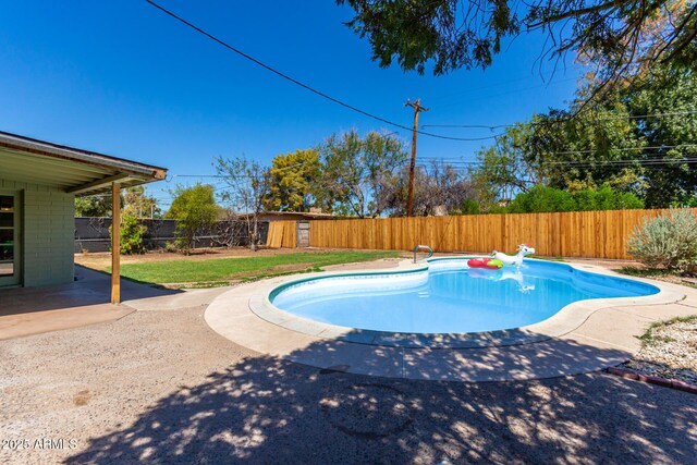 view of pool with a lawn, a storage shed, and a patio