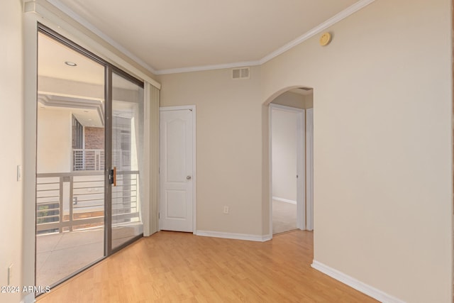 unfurnished room featuring baseboards, visible vents, arched walkways, wood finished floors, and crown molding