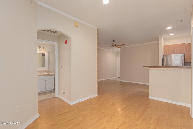 empty room featuring ceiling fan, ornamental molding, sink, and light hardwood / wood-style flooring