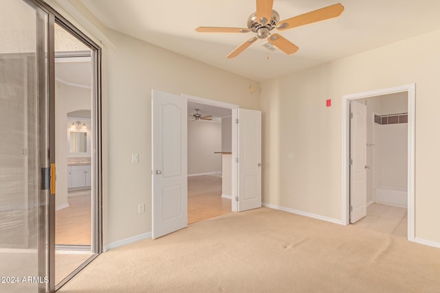 unfurnished bedroom featuring a closet, light colored carpet, ensuite bath, and ceiling fan