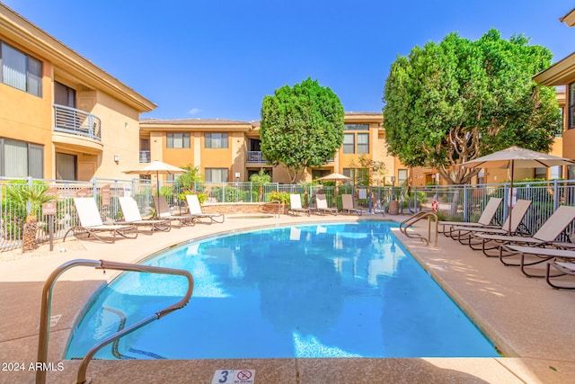 community pool featuring a patio, fence, and a residential view