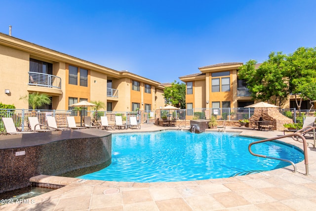 view of swimming pool with a patio area, pool water feature, and a fireplace