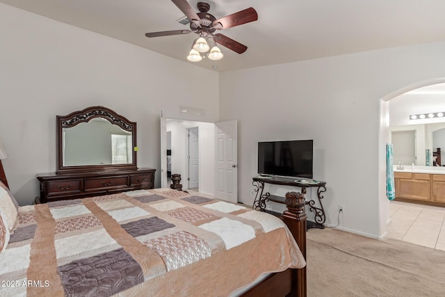 136 N 236th Ave, Buckeye, AZ 85396 - bedroom with connected bathroom, light tile patterned floors, light colored carpet, arched walkways, and ceiling fan