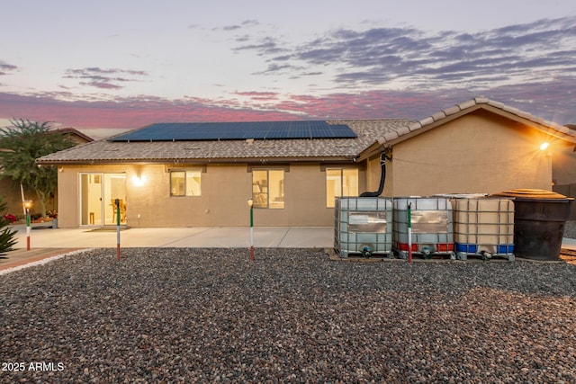 136 N 236th Ave, Buckeye, AZ 85396 - back of property at dusk with stucco siding, a pool, a tiled roof, solar panels, and a patio area