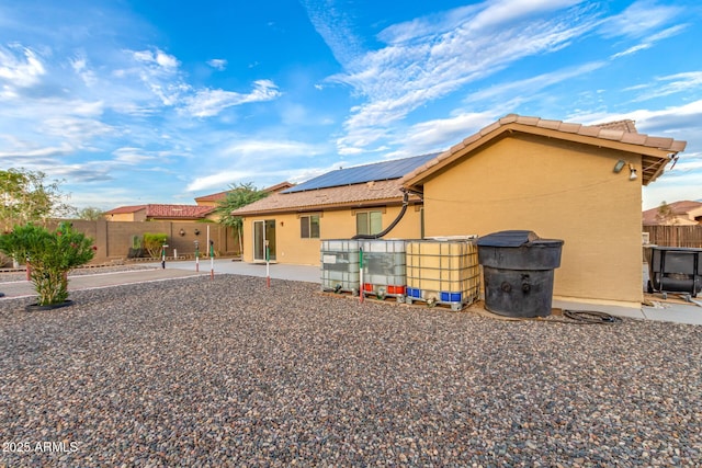 136 N 236th Ave, Buckeye, AZ 85396 - rear view of property featuring fence, roof mounted solar panels, stucco siding, and a patio