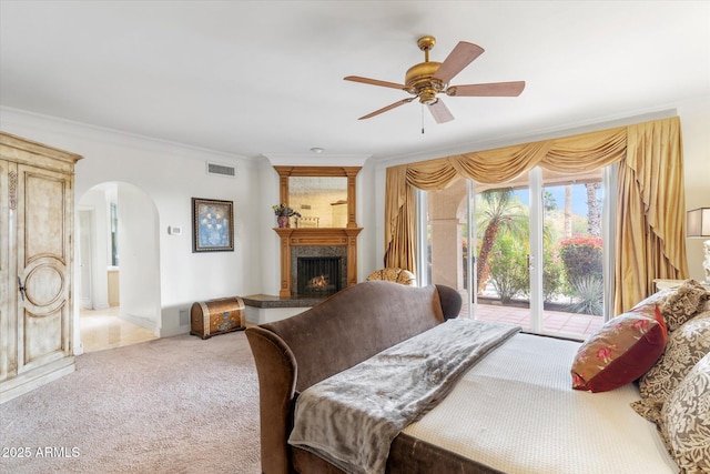 carpeted bedroom with ceiling fan, ornamental molding, access to exterior, and a premium fireplace