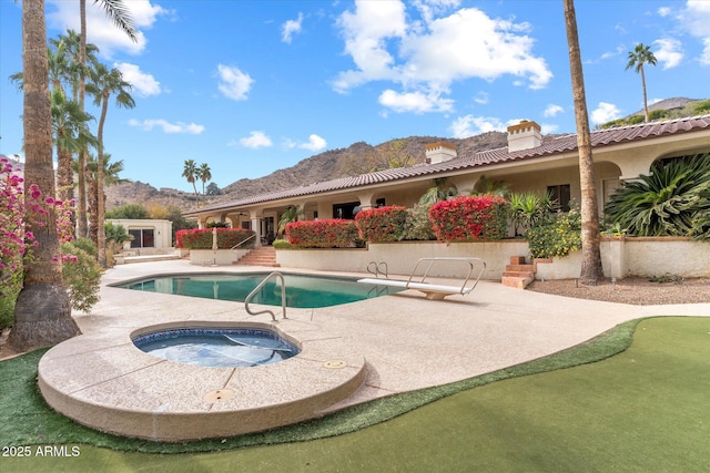 view of swimming pool with an in ground hot tub, a mountain view, and a patio area