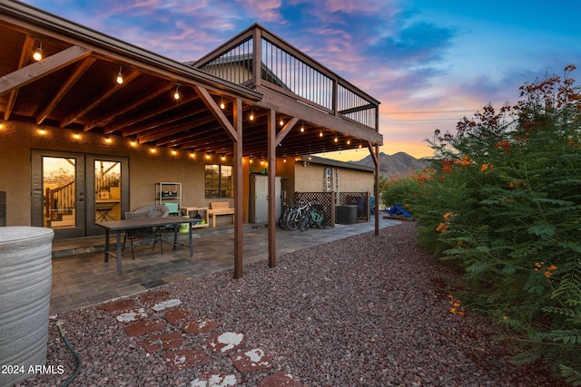 patio terrace at dusk featuring a mountain view and french doors