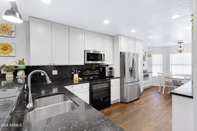 kitchen featuring sink, stainless steel appliances, white cabinetry, and hanging light fixtures