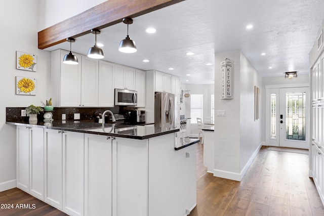 kitchen featuring white cabinetry, hanging light fixtures, kitchen peninsula, and appliances with stainless steel finishes