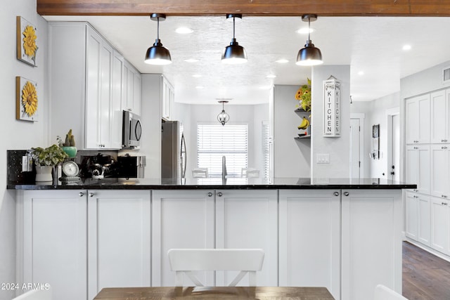 kitchen with appliances with stainless steel finishes, decorative light fixtures, white cabinetry, dark hardwood / wood-style flooring, and sink