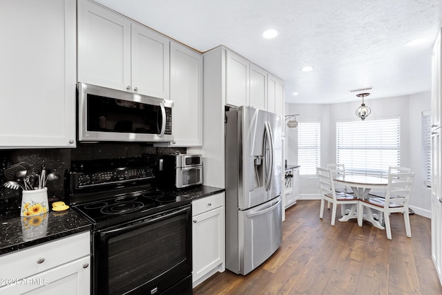 kitchen with white cabinets, stainless steel appliances, dark stone countertops, tasteful backsplash, and dark hardwood / wood-style floors