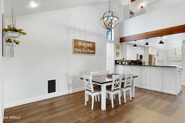 dining area featuring a towering ceiling, a chandelier, and dark hardwood / wood-style floors