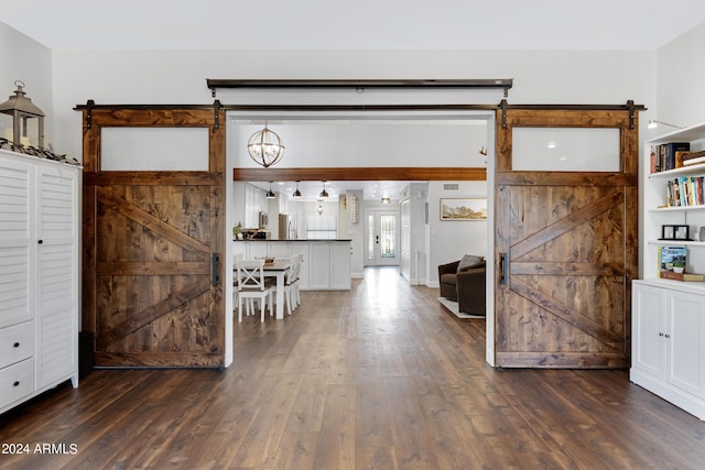 interior space featuring dark hardwood / wood-style flooring, white cabinets, and a barn door