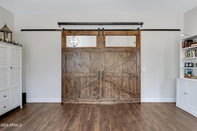 unfurnished bedroom with dark hardwood / wood-style flooring and a barn door