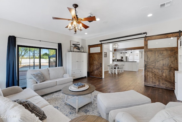 living room with ceiling fan, a barn door, and dark hardwood / wood-style flooring