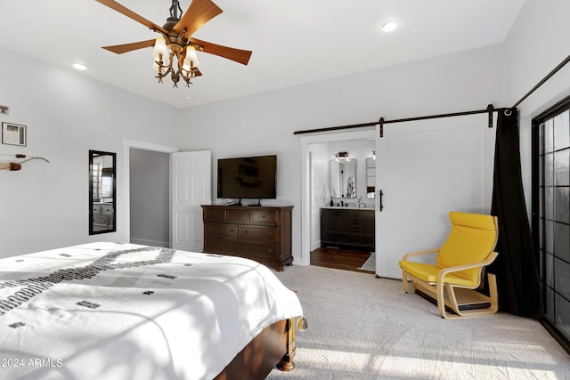 bedroom featuring carpet, ensuite bath, ceiling fan, and a barn door