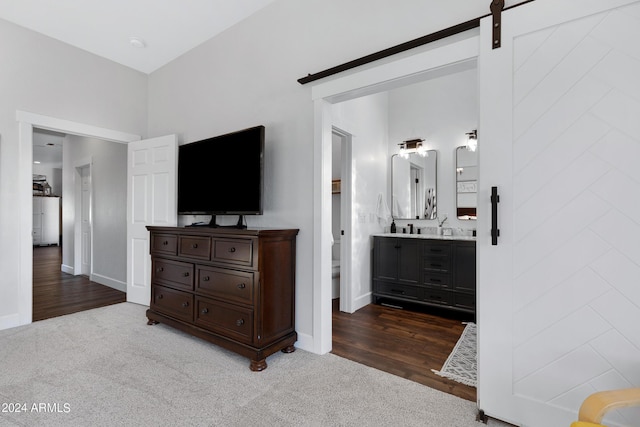 bedroom with dark carpet, ensuite bathroom, and a barn door