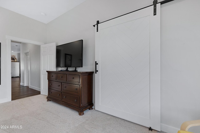 bedroom with light colored carpet and a barn door