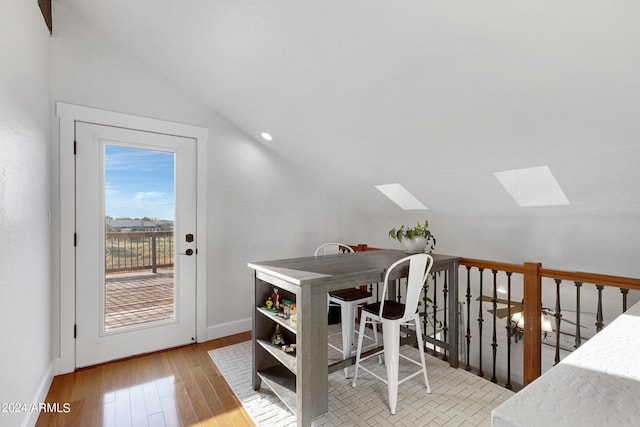 dining area featuring vaulted ceiling with skylight and light wood-type flooring