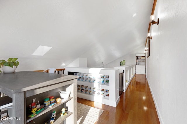 interior space featuring vaulted ceiling with skylight and dark hardwood / wood-style flooring