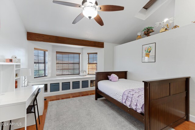 bedroom featuring ceiling fan, light hardwood / wood-style floors, a skylight, and beam ceiling