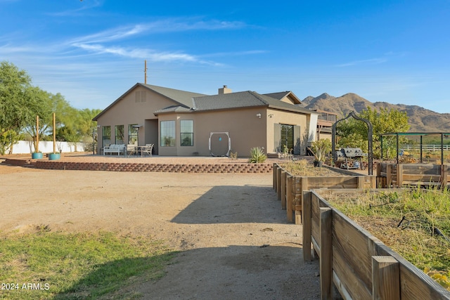 back of property with a mountain view and a patio