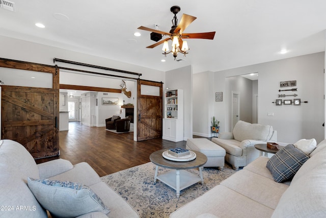 living room with ceiling fan, dark hardwood / wood-style floors, and a barn door