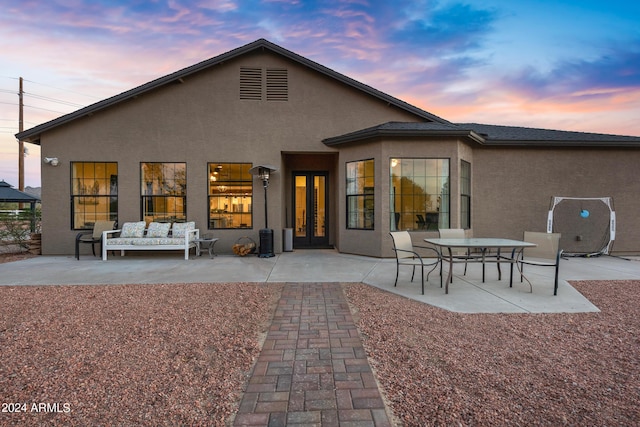 back house at dusk featuring a patio, an outdoor hangout area, and french doors