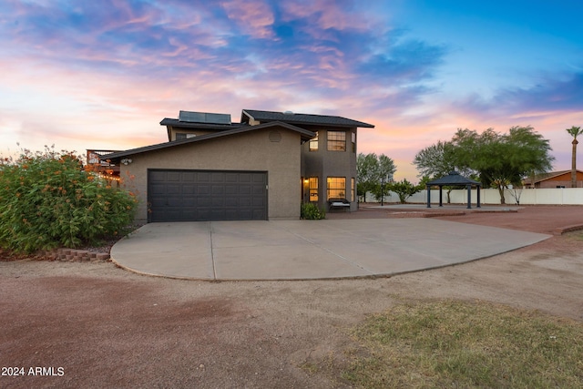 property exterior at dusk featuring a gazebo and a garage