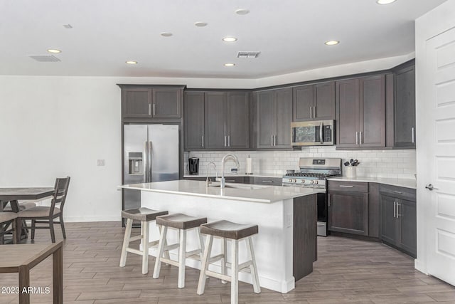 kitchen with sink, a breakfast bar, an island with sink, and appliances with stainless steel finishes