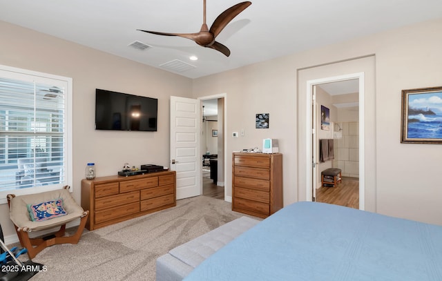 bedroom featuring ceiling fan, ensuite bathroom, and light colored carpet