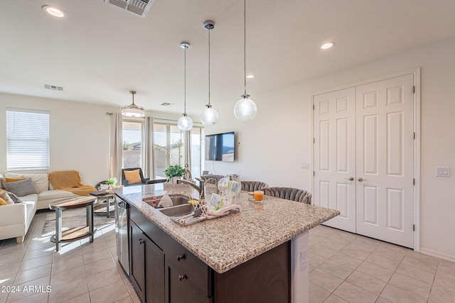 kitchen with sink, an island with sink, decorative light fixtures, and plenty of natural light